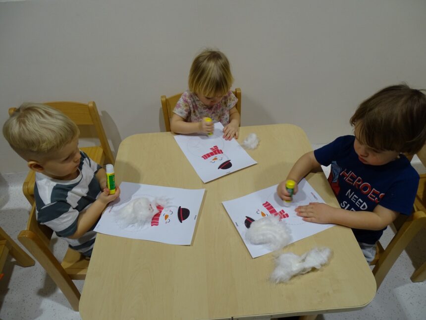 Chłopcy wyklejają bałwanka watą