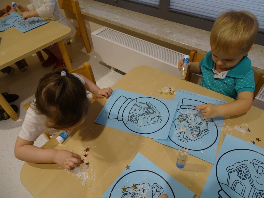 Chłopczyk posypuje obrazek sztucznym śniegiem