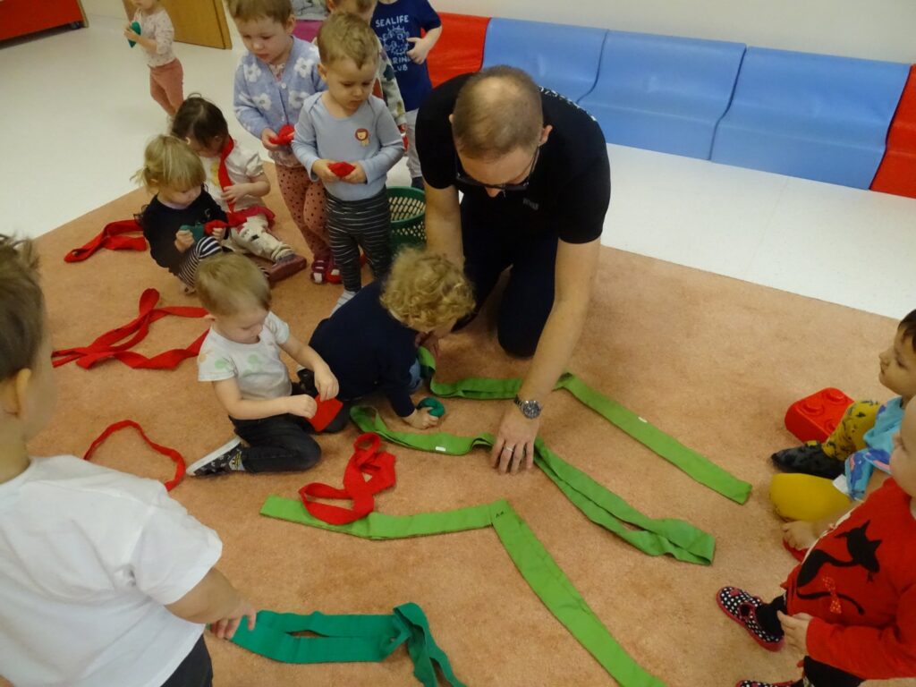 Dzieci wraz z panem próbują stworzyć choinkę