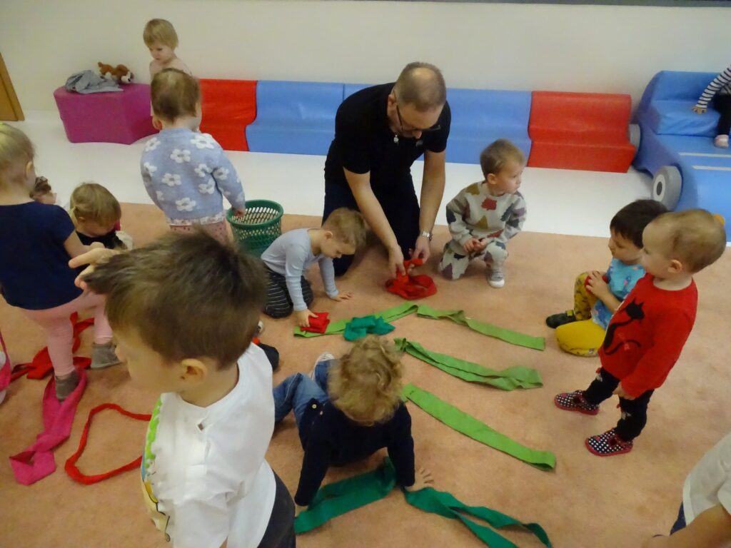 Dzieci pomagają panu stworzyć choinkę z kolorowych szarf