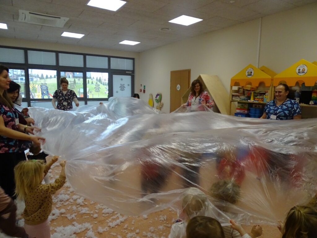 Dzieci bawią się folią tworząc śnieg