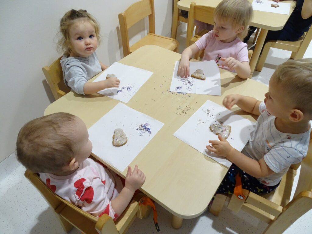 Dzieci posypują pierniczki kolorową posypką