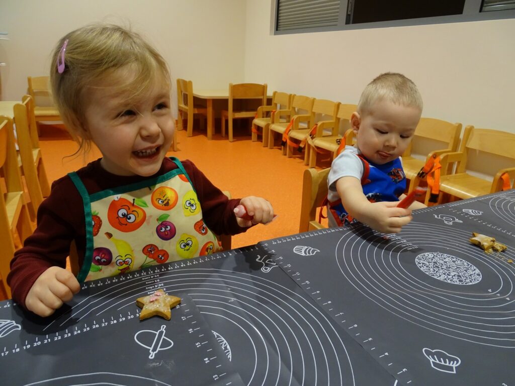 Dziewczynka z uśmiechem dekoruje pierniczka