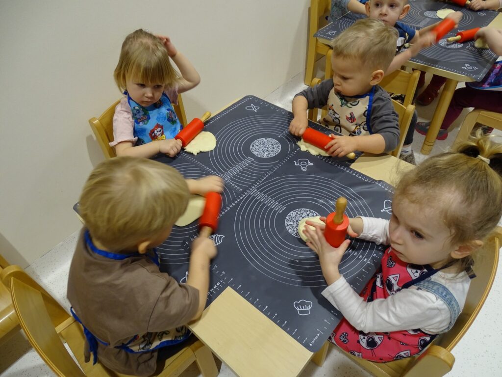 Dzieci ugniatają ciasto na pizzę