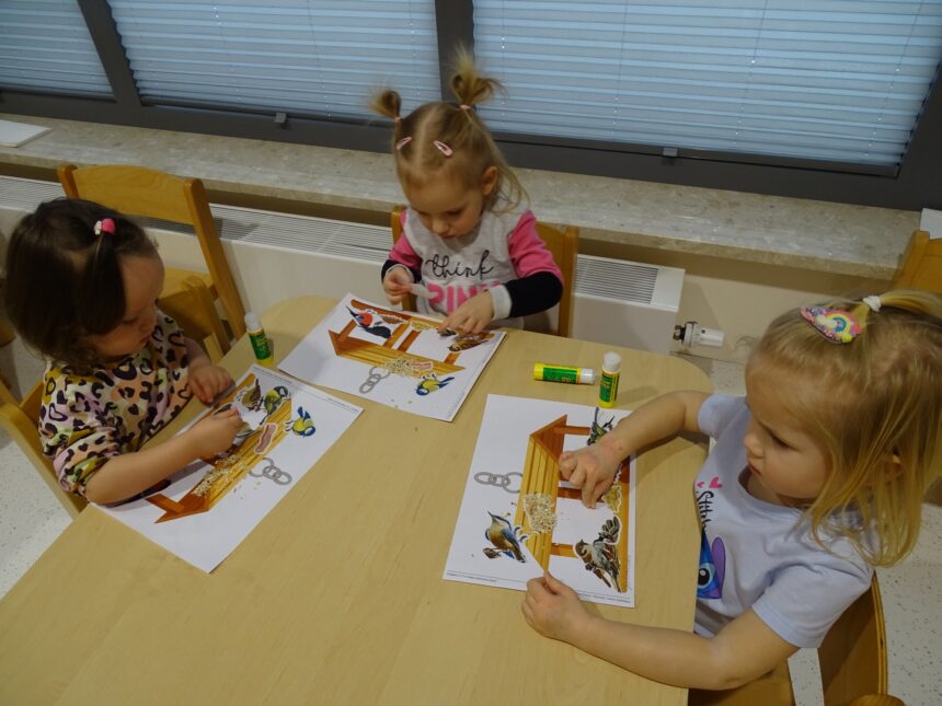 Dziewczynki wklejają ptaszki do karmnika