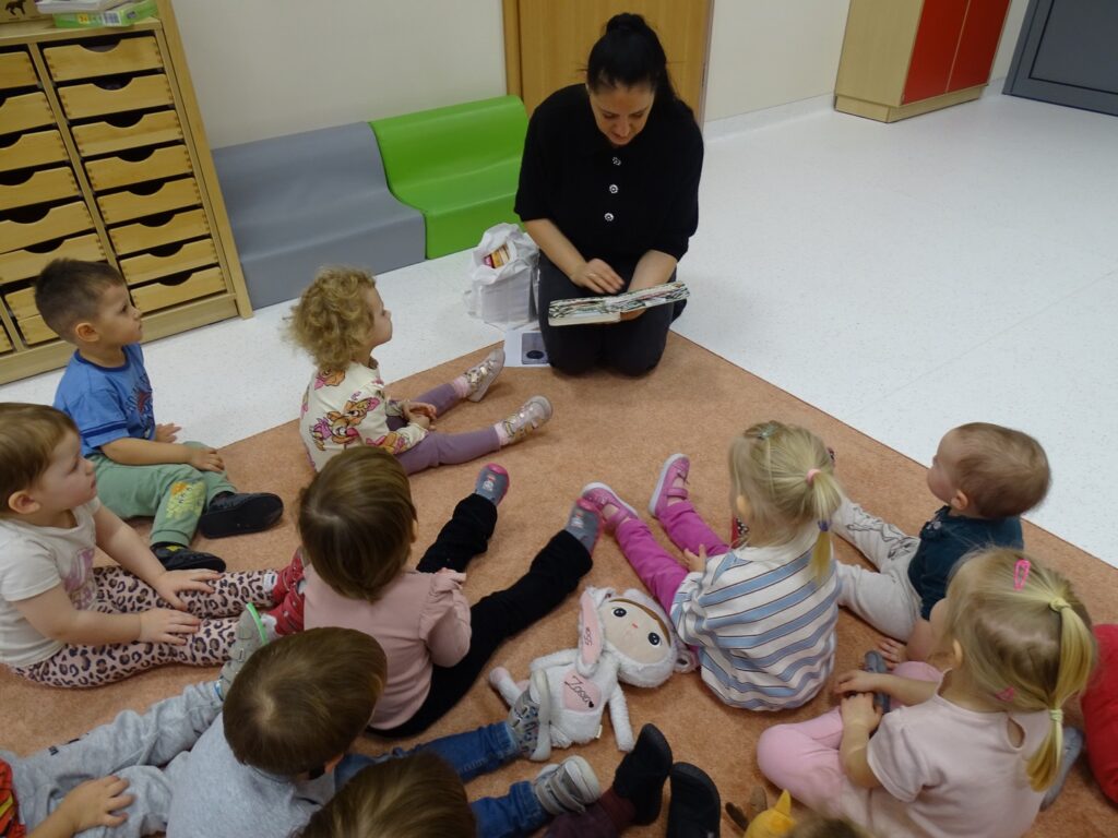 Pani czyta dzieciom książkę o zimowych przygodach