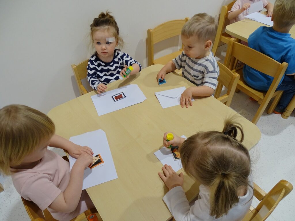 Dzieci naklejają znaczki na koperty