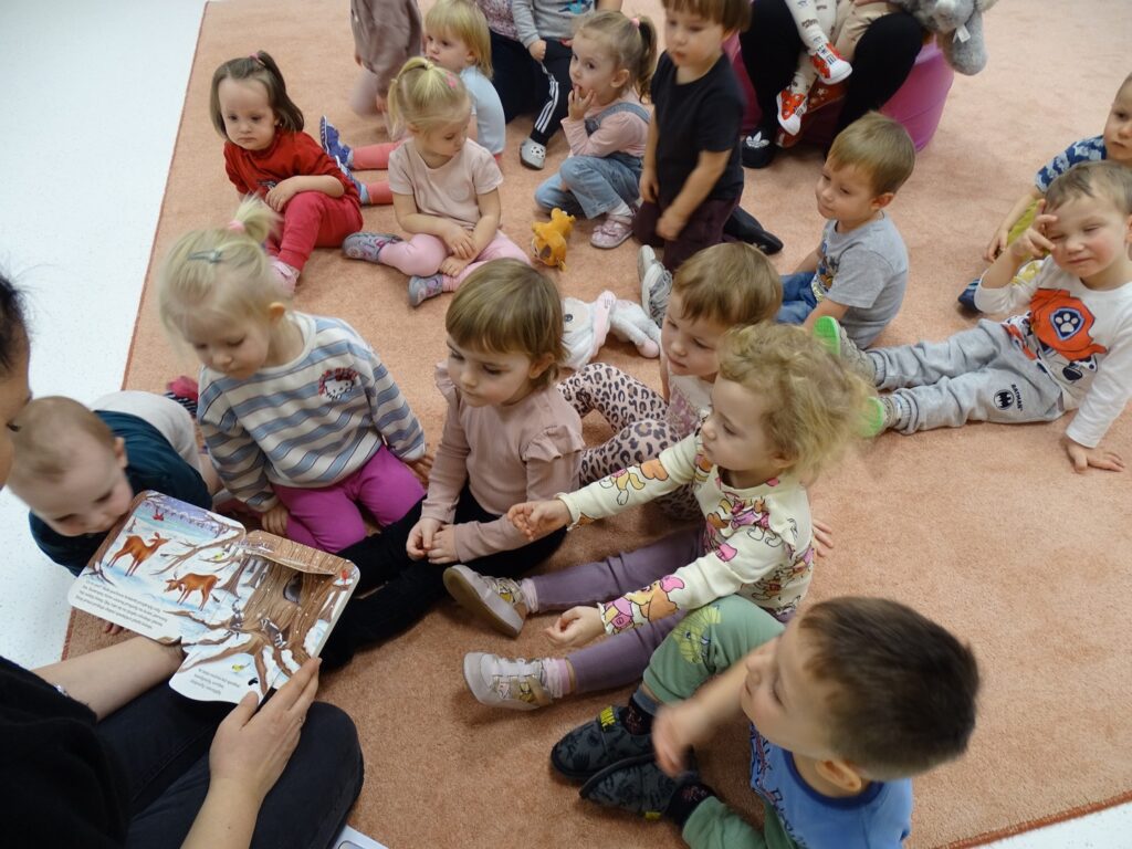 Dzieci z zainteresowaniem słuchają czytanej książki