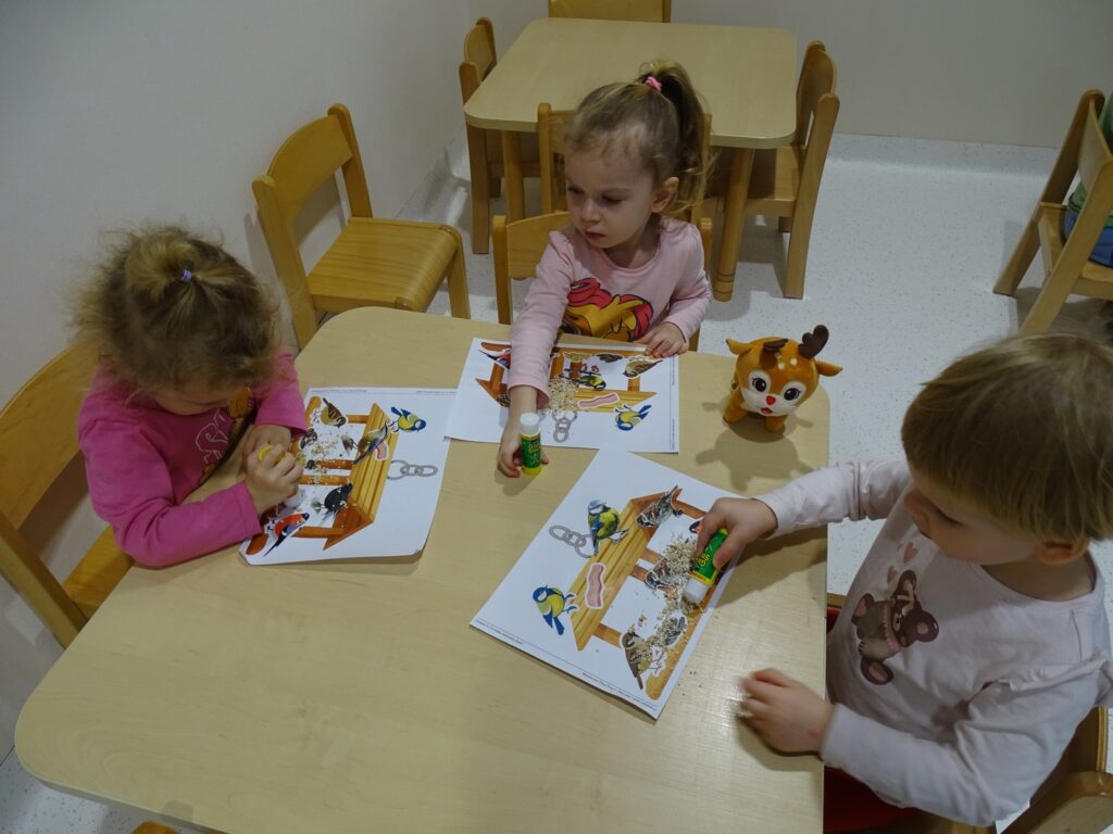 Dziewczynki smarują obrazek klejem