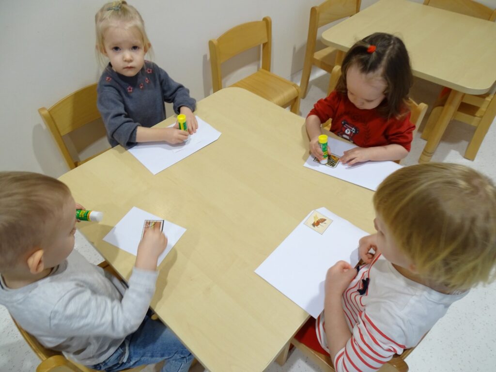 Dziewczynki smarują klejem znaczki