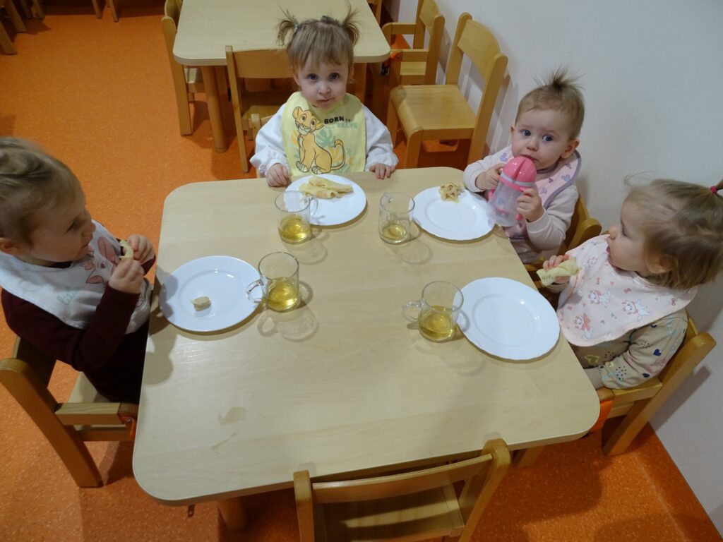 Dzieci przy stoliku jedzą naleśniki