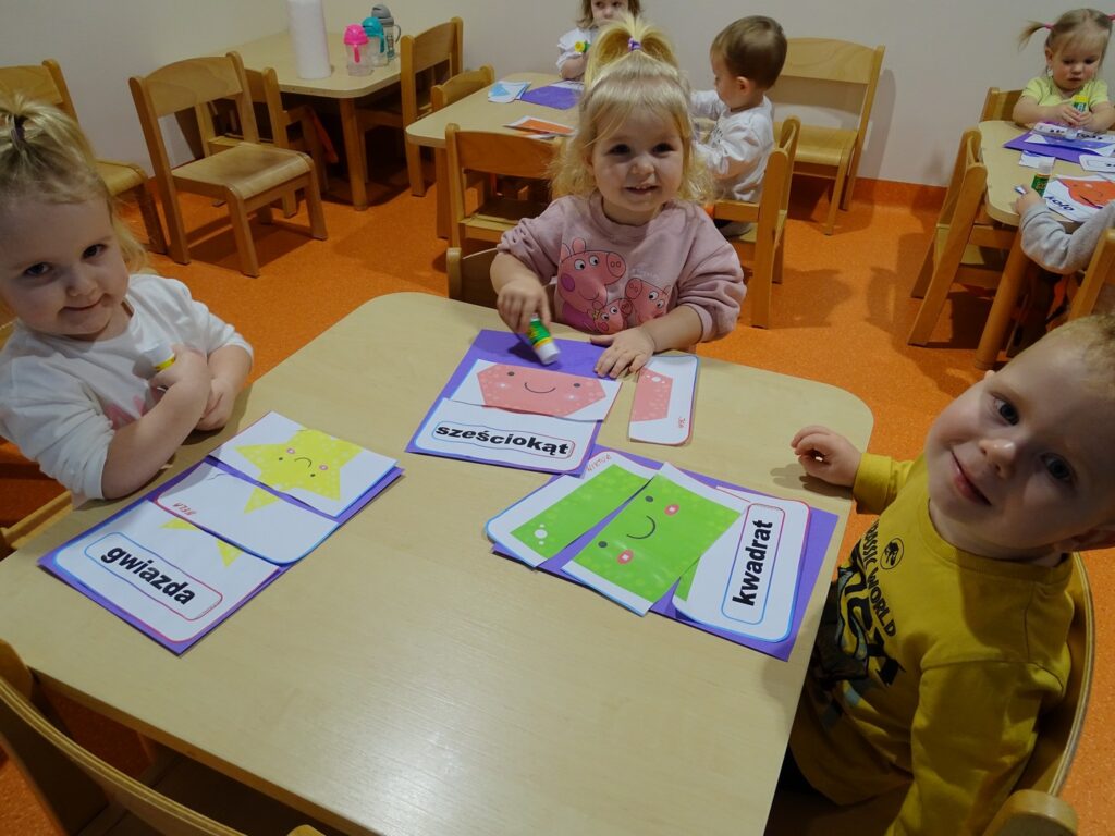 Dzieci przyklejają przy stoliku