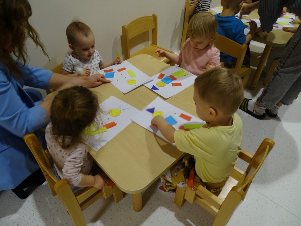 Dzieci wyklejają pajacyka z figur geometrycznych
