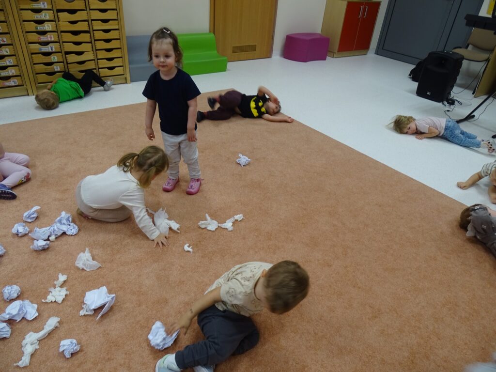 Dzieci zbierają papierowe kulki z dywanu