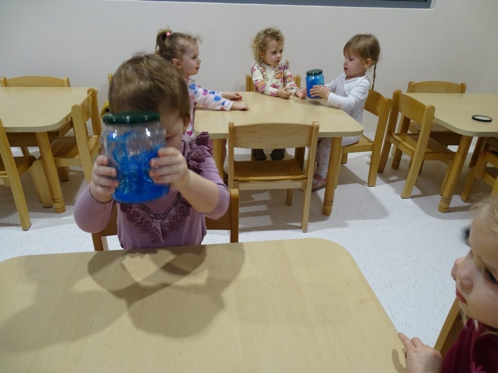 Dziewczynka potrząsa słoikiem tworząc zimową burzę