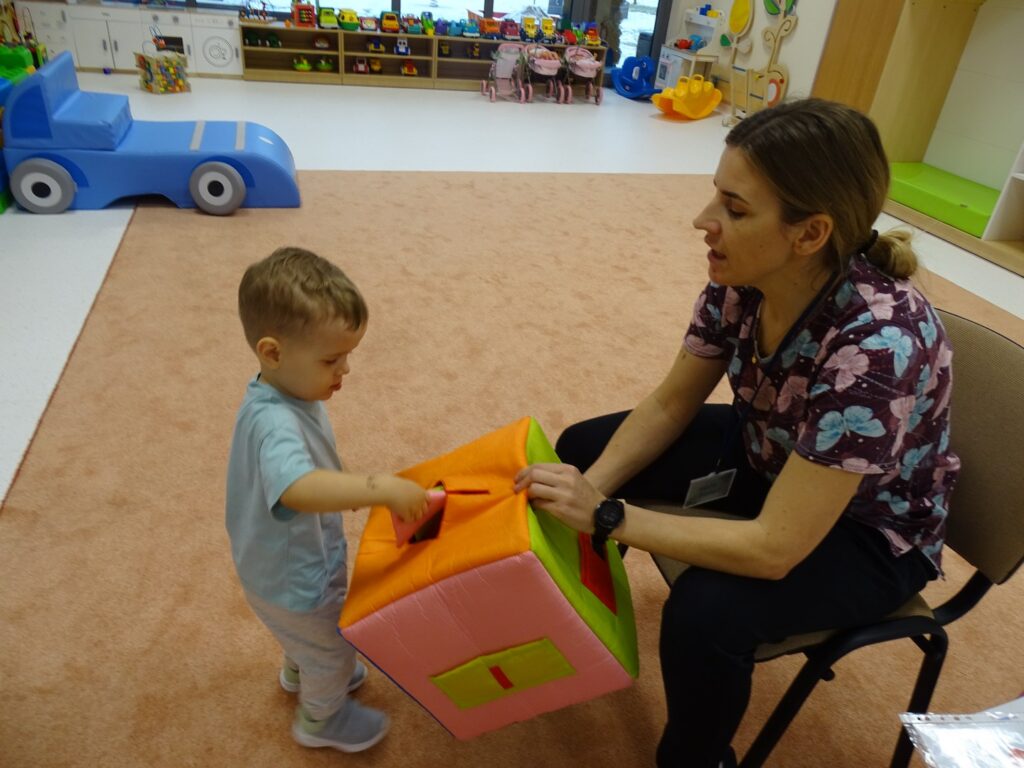 Chłopczyk wyjmuje figurę geometryczną z pudełka