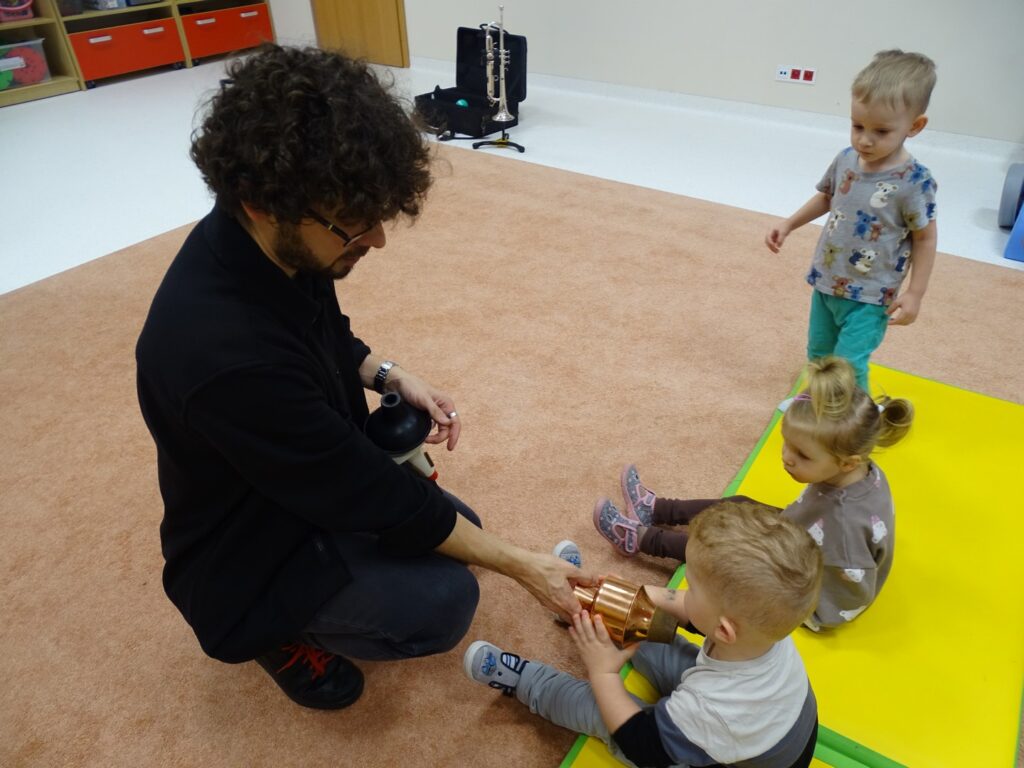 Pan rozdaje dzieciom różne przedmioty