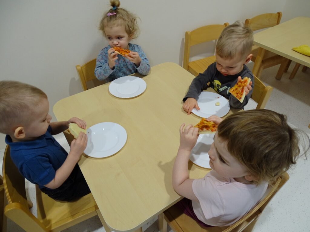 Dzieci z apetytem jedzą pizzę
