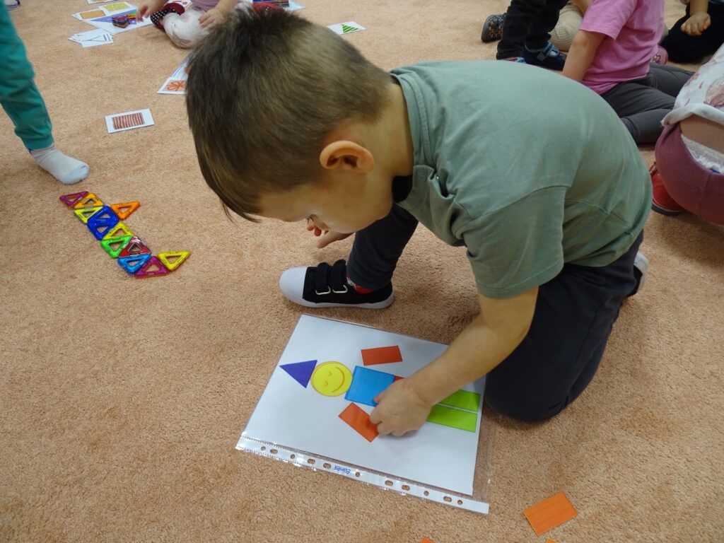Chłopczyk układa ludzika z figur geometrycznych