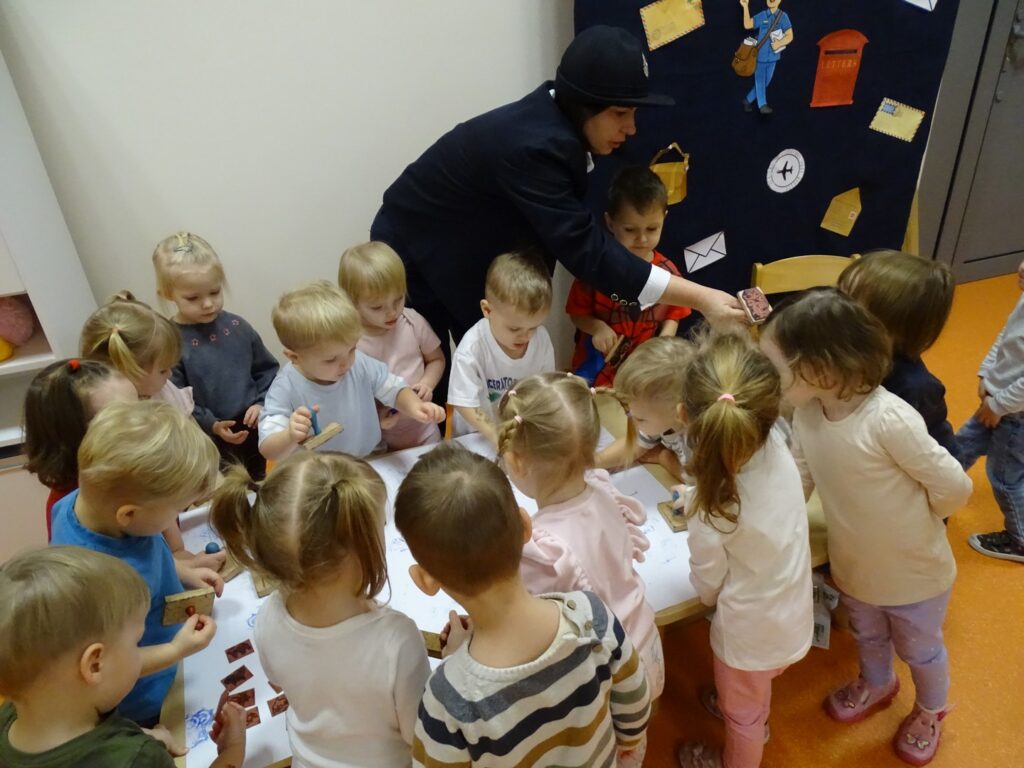 Opiekunka pokazuje dzieciom jak stemplować listy