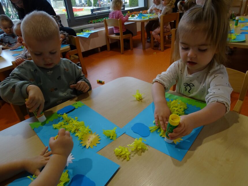 Dzieci smarują kartkę klejem