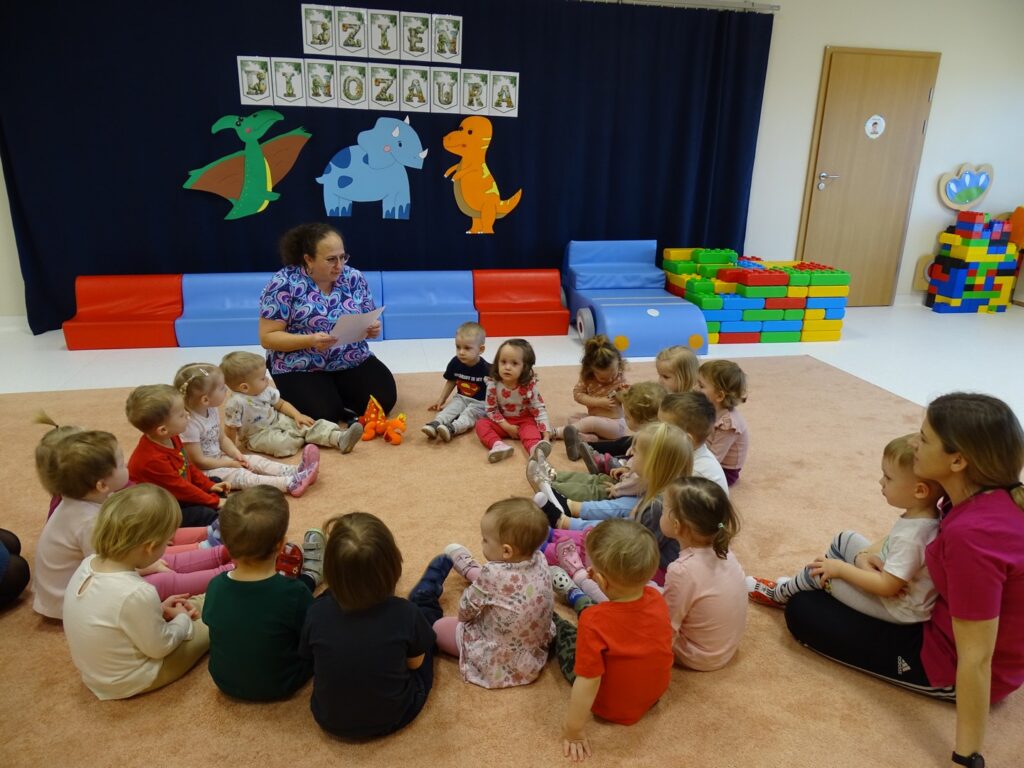 Opiekunka czyta dzieciom o dinozaurach