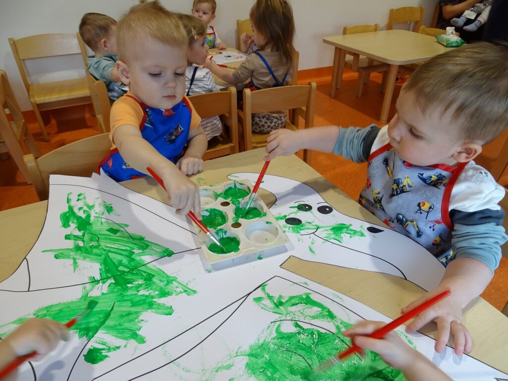 Dzieci malują pędzlami na zielono
