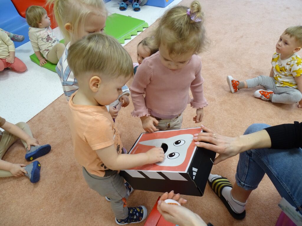 Dzieci wrzucają obrazki do pudełka z ząbkiem