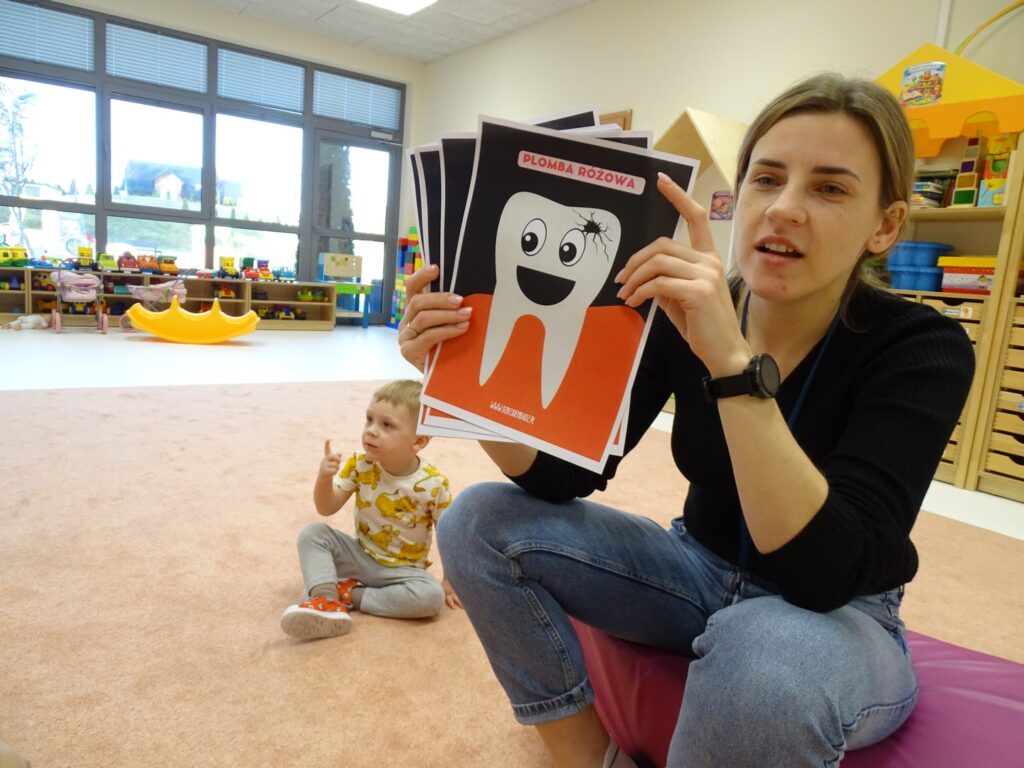 Opiekunka pokazuje dzieciom ząbka z ubytkiem