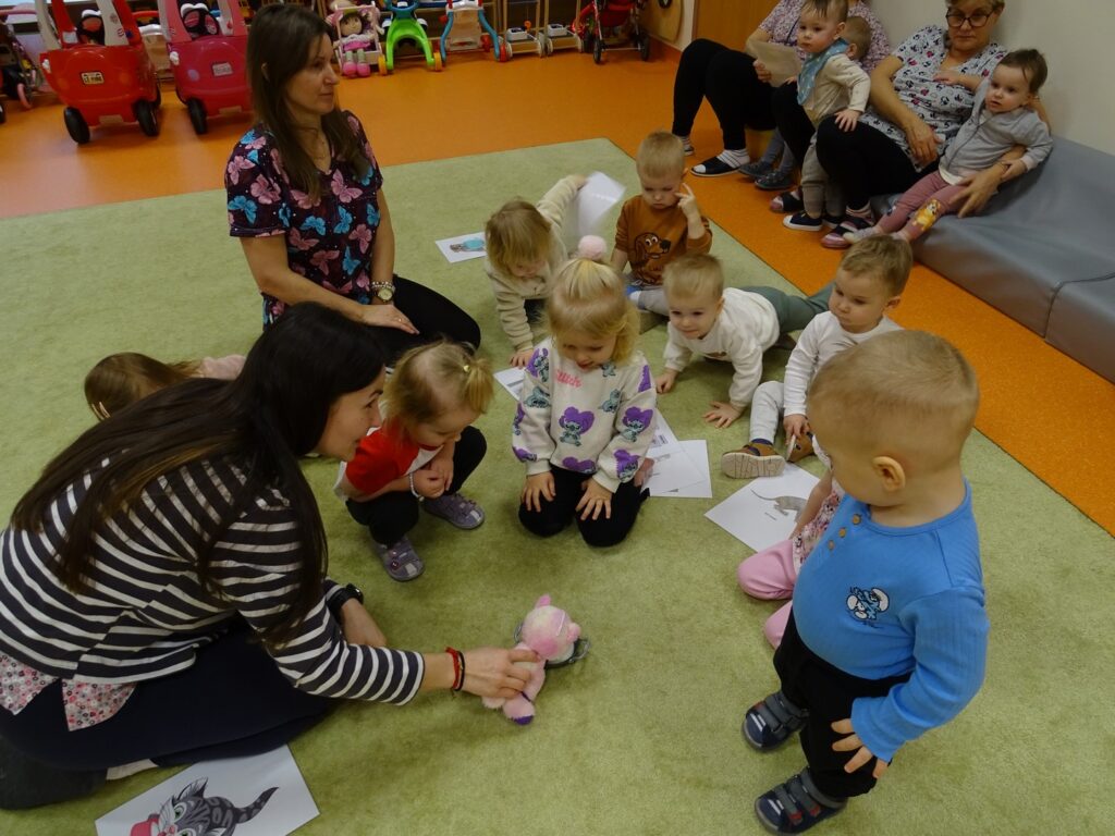 Opiekunowie i dzieci na dywanie