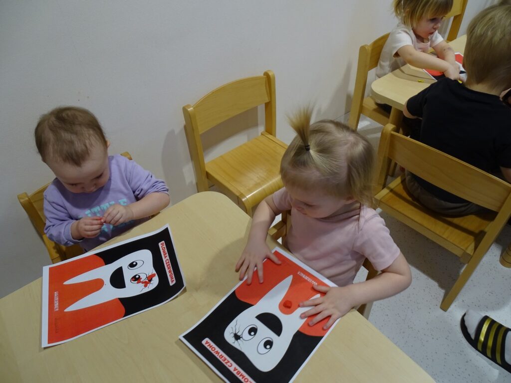 Dziewczynki wyklejają ząbka plasteliną