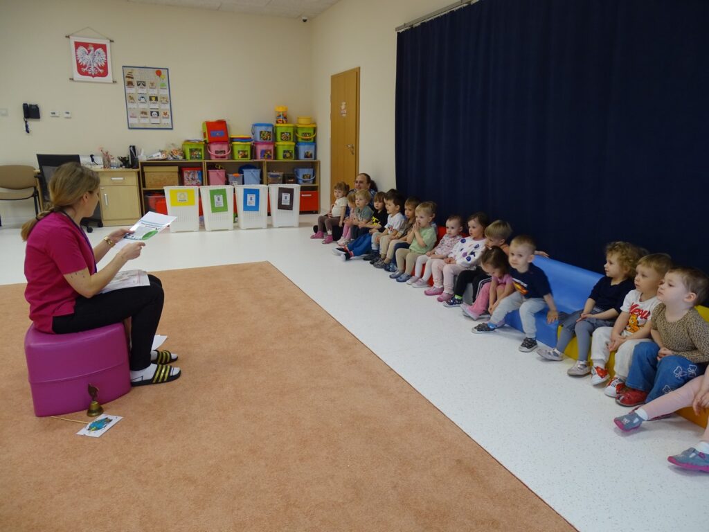 Opiekunka opowiada dzieciom o recyklingu