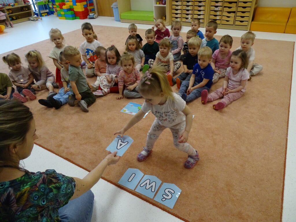 Opiekunka podaje dziewczynce literkę