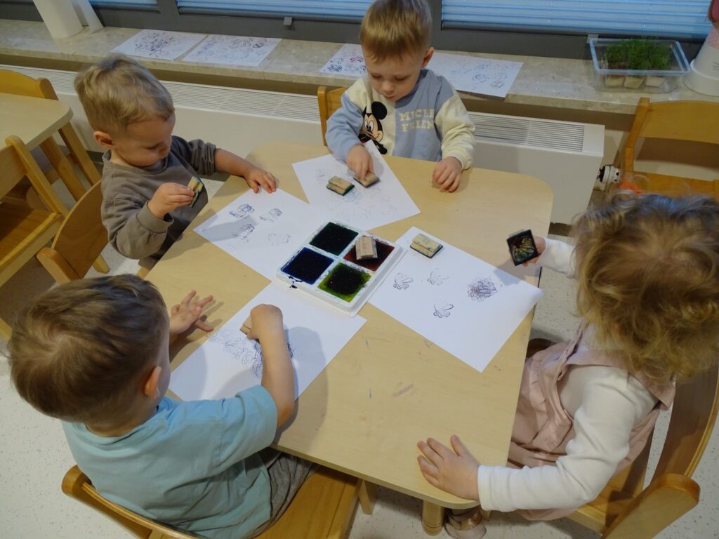 Chłopcy odbijają kolorowe pieczątki