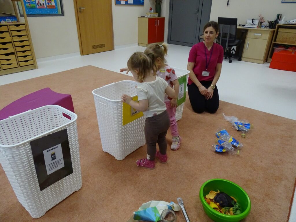 Dziewczynki wrzucają opakowania do kosza