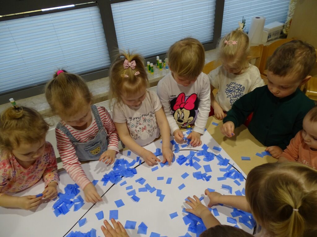Dzieci wyklejają obrazek bibułą