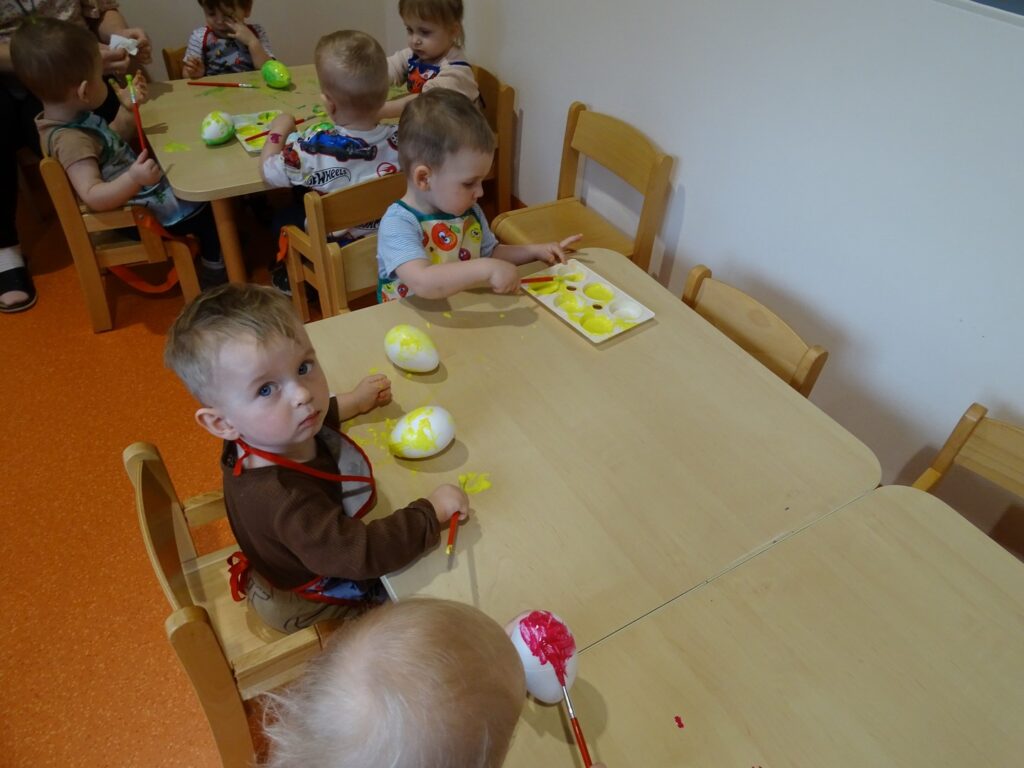 Chłopiec maluje jajko na żółto