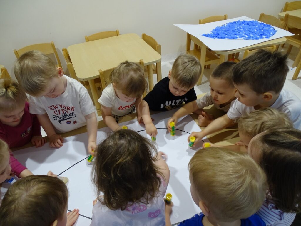 Dzieci smarują obrazek klejem