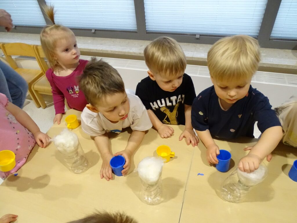 Chłopczyk wkłada watę do butelki