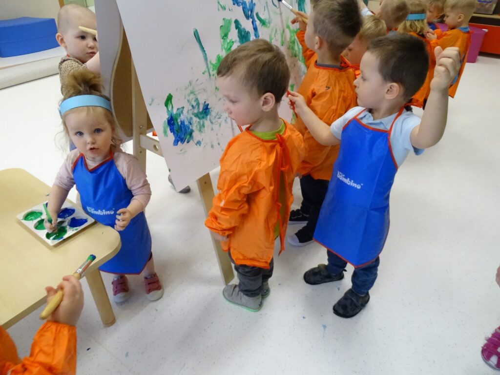 Dziewczynka nabiera farbę na pędzelek