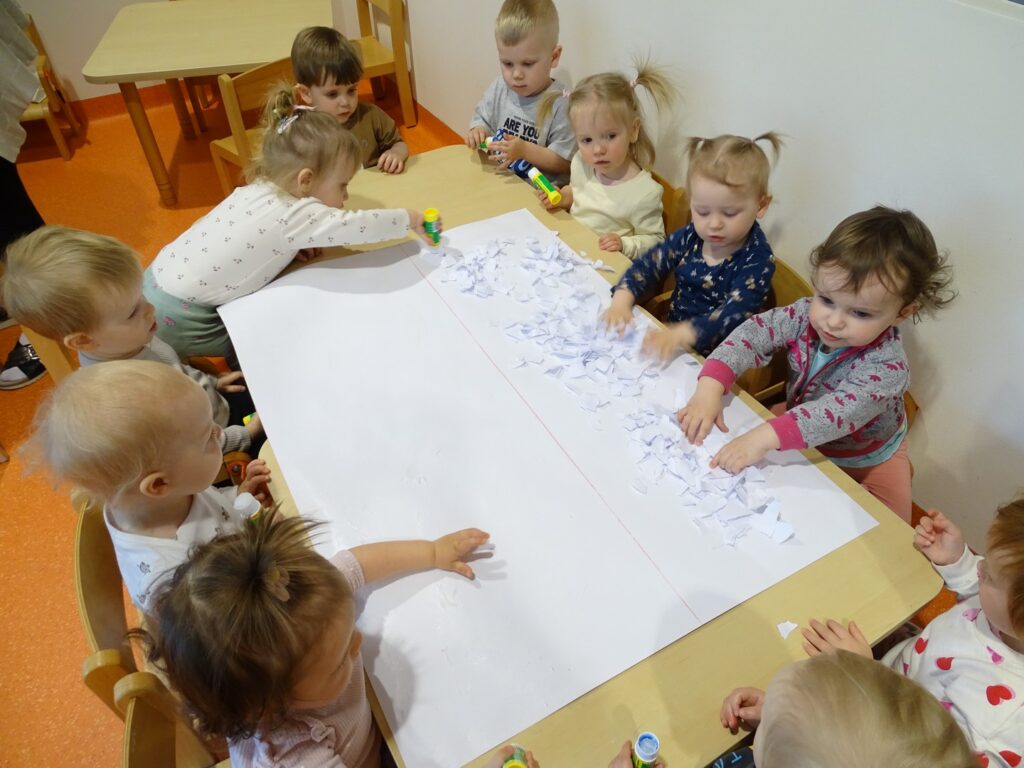 Dzieci przyklejają kawałki białych kartek