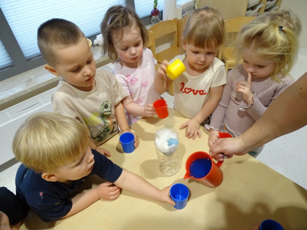 Opiekunka nalewa zabarwioną wodę do kubeczka