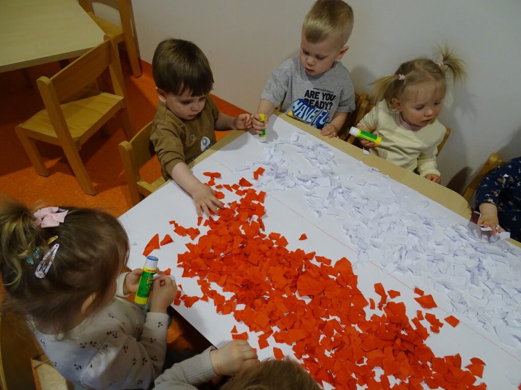 Dzieci siedzą przy stoliku i wykonują pracę
