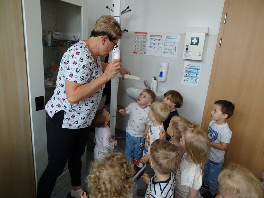 Pielęgniarka pokazuje dzieciom termometr