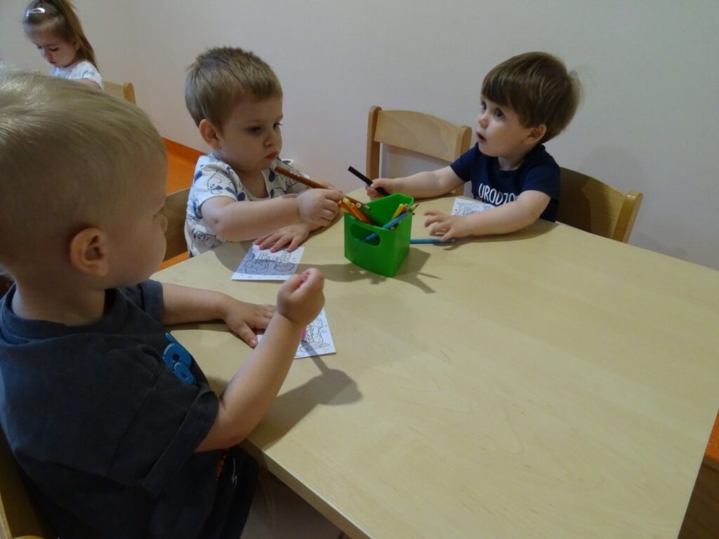 Trzech chłopców maluje kredkami