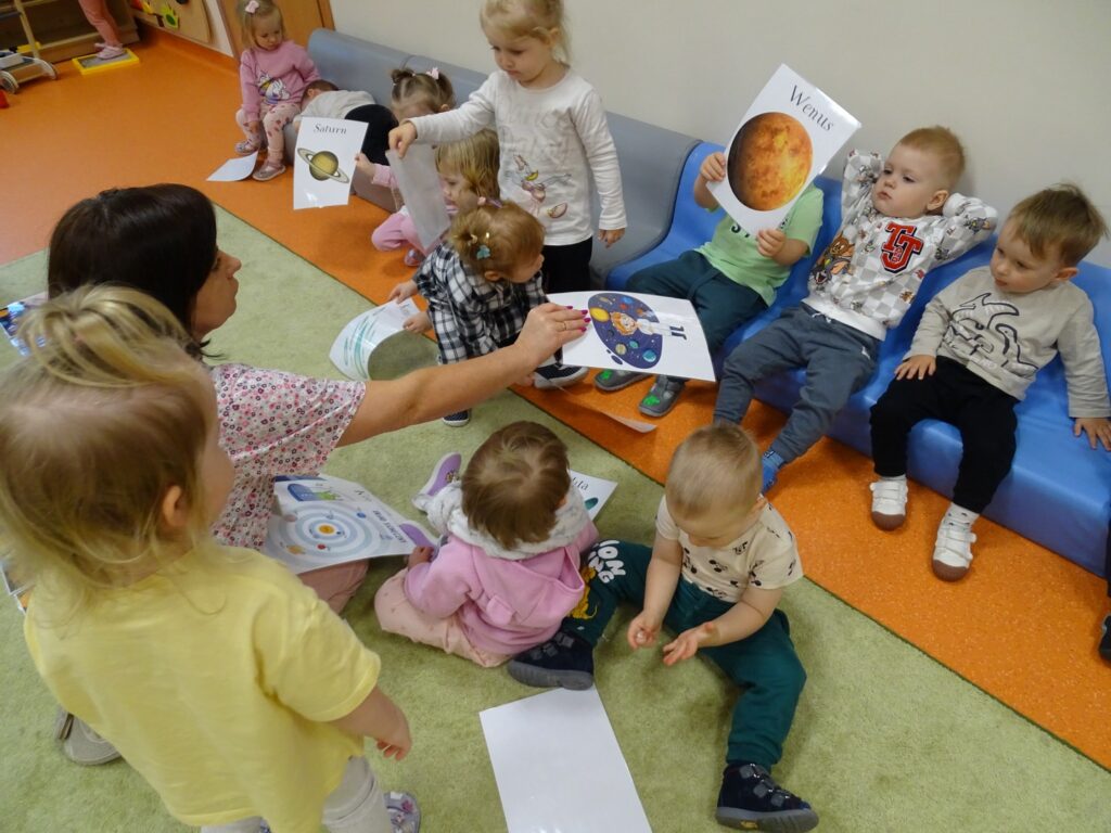 Pani podaje dzieciom karty pracy