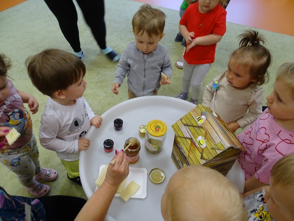 Dzieci stoją przy stoliku i przyglądają się