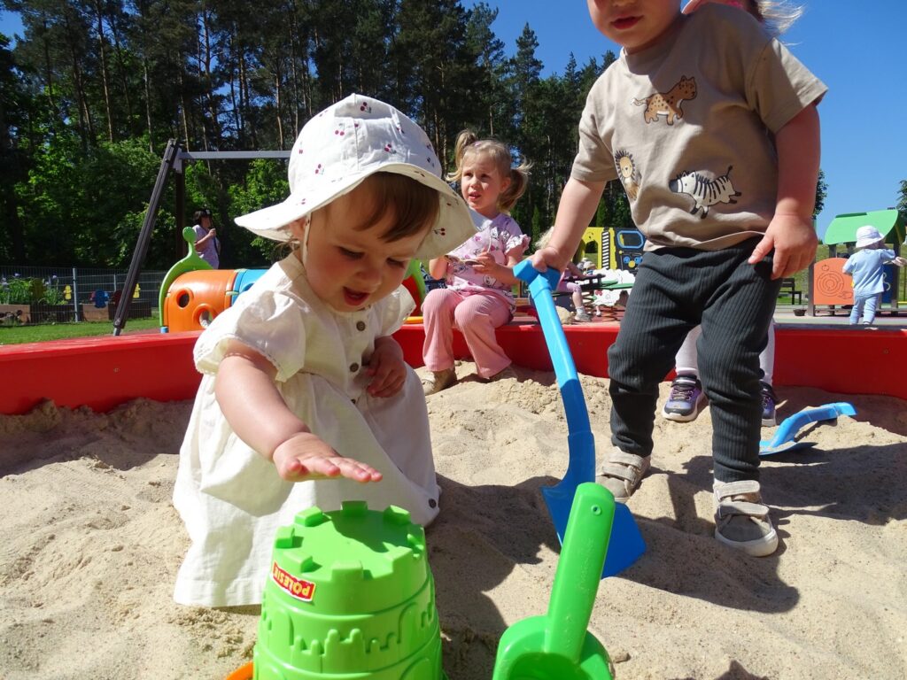 Dzieci w piaskownicy robią babki z piasku
