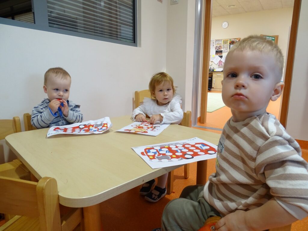 Chłopcy i dziewczynka siedzą przy stoliku