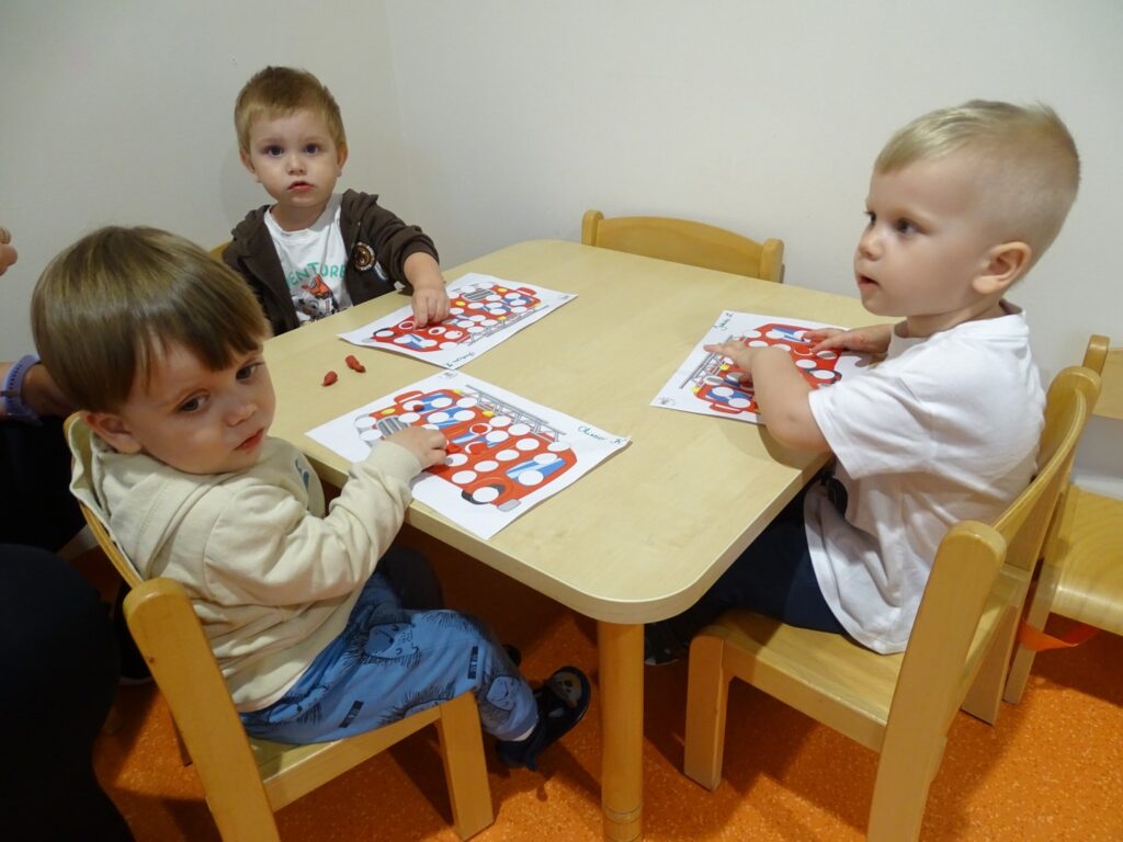 Chłopcy uzupełniają plasteliną pracę